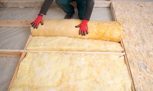 Yellow insulation being rolled out and installed to a floor.